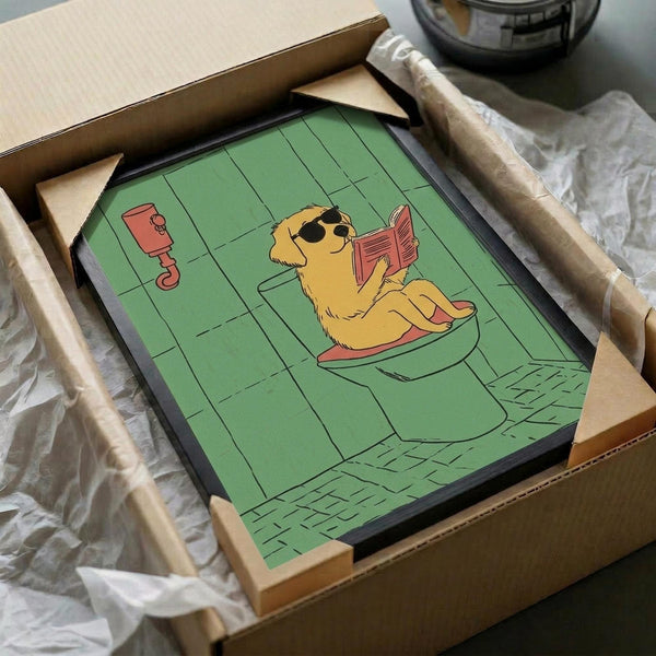 May include: Framed cartoon illustration of a golden retriever wearing sunglasses sitting on a toilet while reading a red book, set against green tiled bathroom walls. The artwork is packed in brown cardboard shipping box with protective wrapping materials visible around the black frame.