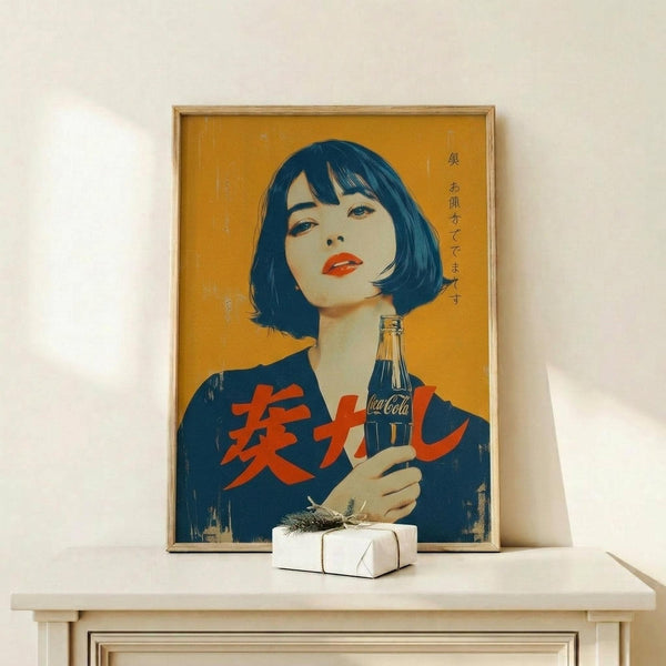 May include: Framed vintage Japanese Coca-Cola advertisement poster featuring woman with black bob haircut and red lips holding glass Coke bottle against yellow background with red Japanese text, displayed on light wood console table next to small white wrapped gift with dried grass decoration