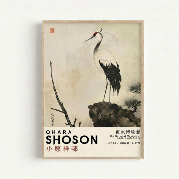 Vintage Japanese woodblock print of a white crane with black wing tips and a red crown, standing on a dark rock beside bare branches. The artwork features traditional East Asian calligraphy and a red seal stamp on cream-colored paper. Exhibition poster text shows "OHARA SHOSON" and details for The National Museum of Modern Art, Tokyo, July 28 - August 16, 1972. Displayed in a light wooden frame against a white wall.