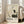 May include: Framed vintage Japanese art poster featuring a white crane with black wing tips and red head detail standing on a dark rock beside bare branches, displayed against a light wooden frame in a bright living room with beige sofa, white walls, and large windows casting natural light across hardwood floors.