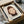 May include: Framed art print featuring minimalist illustration of a young girl with brown bob haircut and green eyes against cream background, displayed in black frame inside cardboard shipping box with protective wrapping materials and wooden dowels