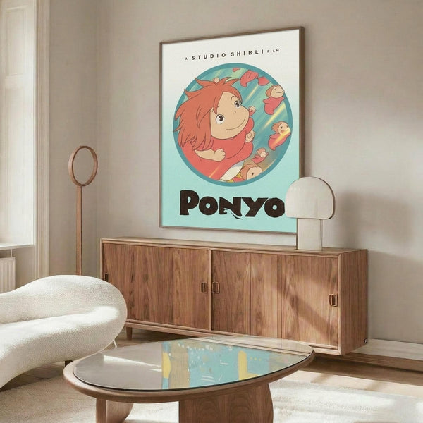 May include: Studio Ghibli Ponyo movie poster print displayed above a mid-century modern wooden credenza in a minimalist living room. The poster features the red-haired character Ponyo in a circular frame against a turquoise background with black text below. Room has cream walls, white modern chair, brass floor lamp, oval glass coffee table, and white table lamp on the credenza.