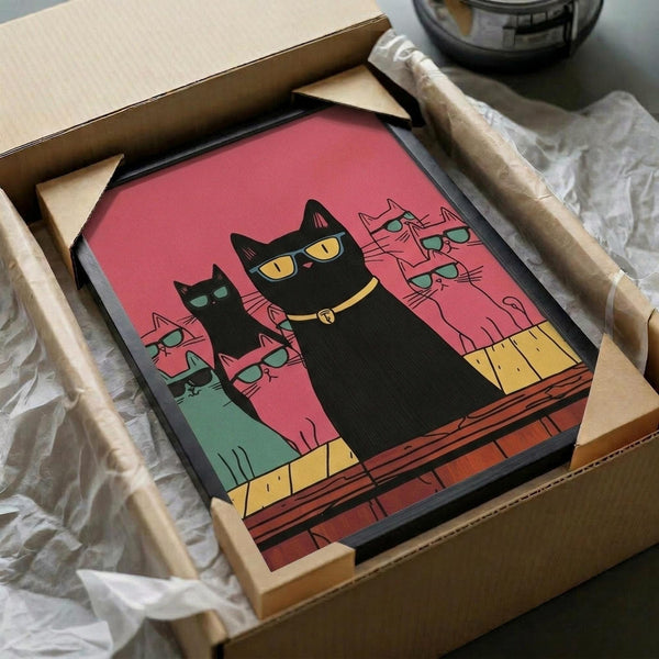 May include: Framed colorful cat illustration artwork being unboxed from shipping materials. Black cat with yellow collar sits prominently on rooftop with pink and coral background. Multiple outline cats with sunglasses fill the scene. Vibrant retro color palette includes coral pink, orange, yellow and teal. Print appears mounted in dark frame, surrounded by protective packaging materials and cardboard box.