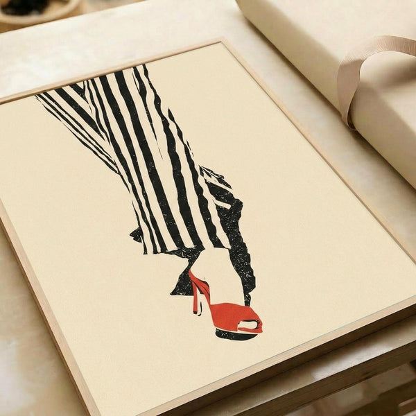May include: Minimalist fashion illustration print displayed in light wood frame on cream colored surface with kraft paper roll. Artwork shows woman's legs in black and white striped wide-leg pants with red high heels against beige background. Clean, modern styling with neutral tones and simple composition.