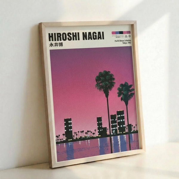 May include: Framed poster print leaning against white wall showing stylized cityscape silhouette with palm trees against gradient pink-purple sunset sky, water reflection below, in light wood frame on white surface
