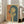 May include: Framed vintage-style poster leaning against white wall next to beige sofa in bright living room. Artwork shows woman with dark bob haircut holding cigarette, rendered in retro Japanese pop art style with yellow, teal and coral colors. Red Japanese characters visible on left side. Natural sunlight streams through windows onto hardwood floors.
