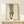 May include: Framed fashion illustration showing legs wearing black and white striped pants with red high heels, displayed on light wood console table next to small wrapped gift with greenery. Minimalist artwork in natural wood frame against cream wall in modern interior setting.