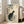 May include: Framed Japanese-style artwork featuring a black and white cat sitting among flowering rose branches with green leaves on cream background, displayed in light wood frame leaning against white wall next to beige upholstered sofa in bright living room with large windows