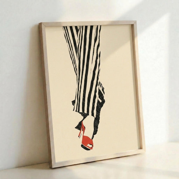 Minimalist fashion illustration showing the lower half of a person wearing black and white vertical striped pants with red high-heeled sandals, displayed in a light wooden frame against a white wall on what appears to be a white surface.