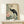 May include: Framed vintage-style Japanese art print featuring a black crane with red crown plume standing among coral pink peonies and water lilies in muted green tones, displayed on light wood console table beside white wrapped gift box against cream wall
