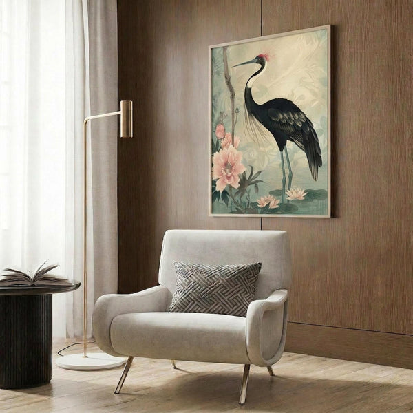 May include: Japanese-style artwork featuring a black crane with red head crest standing among pink peonies and water lilies, displayed in light wooden frame on wood-paneled wall above beige upholstered chair with geometric throw pillow, brass floor lamp and dark side table with open book nearby