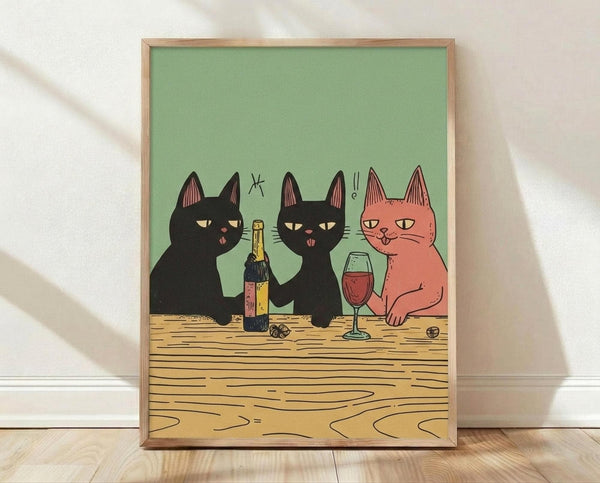 May include: Framed poster print leaning against white textured wall on light wood floor. Artwork shows three cats sitting at wooden table - two black cats and one orange cat - sharing wine with bottle and glass. Green background, cartoon illustration style in natural wood frame.