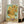 May include: Framed reproduction of Van Gogh's famous sunflowers painting leaning against white wall in bright living room. Yellow sunflowers in ceramic vase against turquoise background, displayed in light wood frame. Modern beige armchair and large windows with natural light visible in background. Artwork shows thick brushstrokes and vibrant colors characteristic of post-impressionist style.