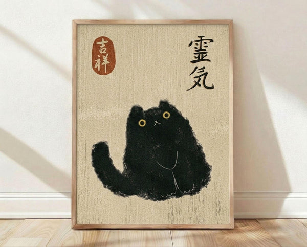 May include: Framed poster artwork leaning against white wall on light wood floor. The print features a minimalist black ink-style cat sitting upright with yellow eyes and simple facial features on textured beige background. Japanese characters appear in black on the right side and within a red oval seal on the left. Natural wood frame surrounds the artwork in this clean, modern room setting.