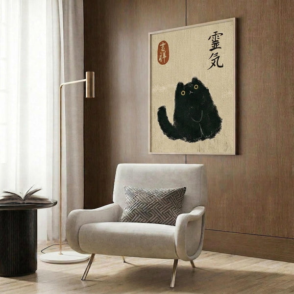 May include: Black cat artwork with Japanese calligraphy characters and red seal stamp on cream background, displayed in light wood frame above beige upholstered armchair with geometric patterned pillow. Modern reading nook with gold floor lamp, dark round side table with open book, and warm wood paneled walls.