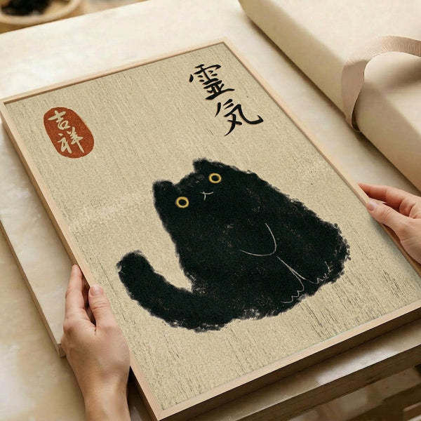 Hands holding a beige textured art print featuring a black cat illustration with yellow eyes in Japanese ink wash style. The print includes Japanese calligraphy characters and a red seal stamp in the upper portion. The artwork is displayed on white paper wrapping with a beige ribbon visible in the background.