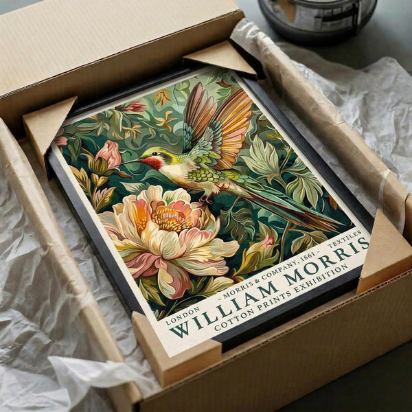 May include: Vintage-style botanical poster featuring colorful hummingbird with spread wings flying among lush green foliage and large pink peony flowers. Print shown in black frame inside cardboard shipping box with white tissue paper packaging on white fabric surface.