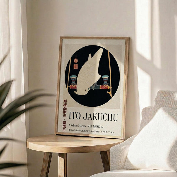 May include: Framed art print displaying a white parrot perched on decorative stands within a black circular background, featuring Japanese text and museum attribution below. The wooden-framed poster sits on a round wooden stool beside a beige upholstered chair, with plant shadows creating soft lighting patterns on neutral walls in a minimalist interior setting.