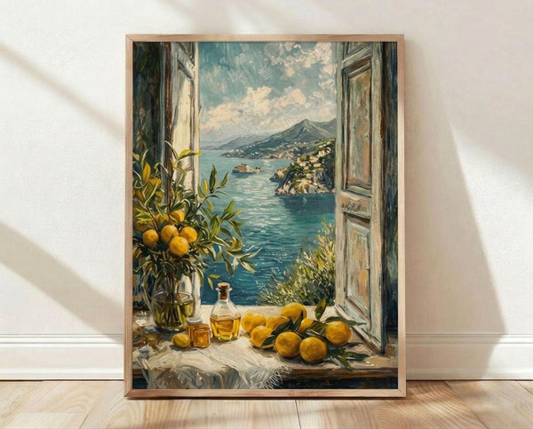 May include: Framed poster print leaning against white wall on light wood floor. Artwork shows Mediterranean coastal scene through open window with weathered shutters. Foreground features scattered yellow lemons, glass bottle with golden liquid, and lemon branch in vase on white cloth-covered windowsill. View reveals turquoise waters, hillside village with white buildings, and mountain backdrop under cloudy sky. Warm natural lighting creates shadows on wall.