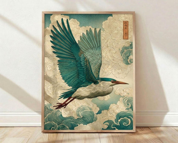 May include: Framed poster print featuring a blue-green heron in flight with outstretched wings, surrounded by stylized cream and teal clouds and waves in traditional Japanese art style. The bird has a long pointed beak and reddish legs. A red Japanese character seal appears in the upper right corner. The artwork is displayed in a light wooden frame, leaning against a white wall on light wood flooring with soft natural lighting casting shadows.