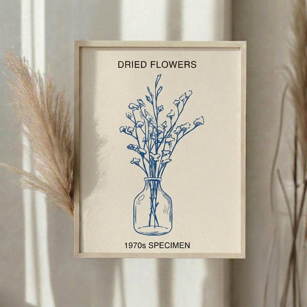 May include: Framed botanical wall art showing blue line drawing of dried flowers in a glass vase on cream background, displayed on neutral wall beside dried pampas grass stems in soft natural lighting