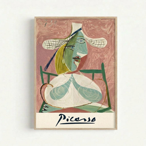 Framed cubist-style artwork featuring a woman with green and yellow facial features, white hat with checkered pattern, and exposed breasts rendered in pale green and white tones. The figure sits in a green chair against a textured pink background. Below the artwork is a signature reading "Picasso" in black script lettering on white background. The piece is displayed in a thin natural wood frame against a light wall.