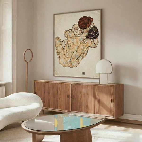 May include: Framed Egon Schiele artwork showing two embracing figures with reddish and dark hair on cream background, displayed above walnut credenza in modern living room with white sculptural chair, oval glass coffee table, and warm natural lighting