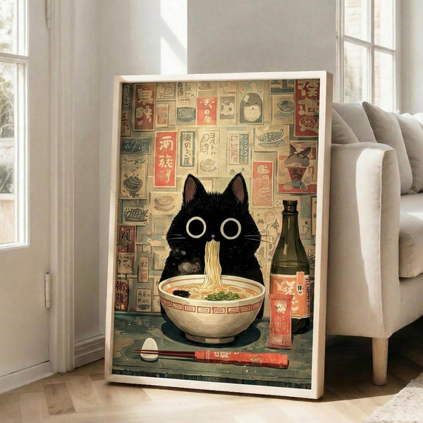 May include: A framed poster displaying a cute black cat with large round eyes sitting behind a bowl of ramen noodles. The artwork features a vintage Japanese aesthetic with a collage-style background of food advertisements and text in muted colors. The white-framed print leans against a wall next to a beige sofa in a bright, modern living room with hardwood floors and large windows.