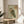May include: Framed vintage Japanese woodblock print featuring a detailed owl with brown and green feathers, surrounded by traditional calligraphy characters on pale green background, displayed on round wooden side table next to beige upholstered chair and plant leaves in bright, naturally lit room with white walls.