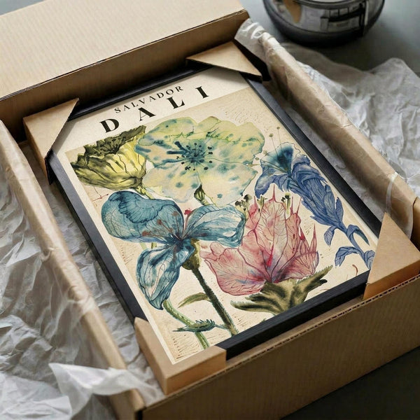 May include: Framed botanical watercolor print featuring delicate flowers in soft blues, greens, and coral pink tones, displayed in black frame inside cardboard shipping box with protective tissue paper wrapping on white surface