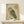 May include: Framed Japanese woodblock-style owl print in natural wood frame, displayed on light wooden shelf. The artwork features a detailed brown and green owl with large round eyes against pale background, with red Japanese calligraphy characters in upper right corner. Small wrapped white gift box with evergreen sprig sits beside the frame on the shelf.