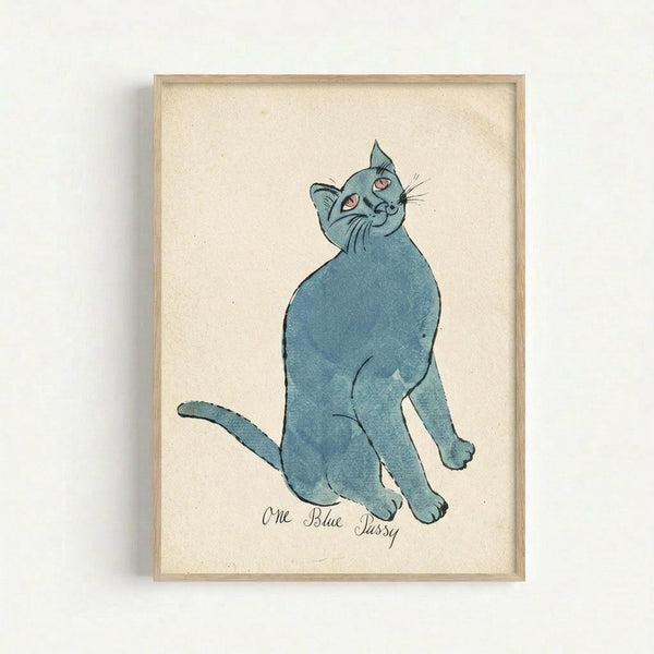 Framed illustration of a blue cat sitting upright with its head tilted back and eyes looking upward. The cat is rendered in soft blue watercolor tones against a cream-colored textured paper background. Below the cat is handwritten text reading "One Blue Pussy" in cursive script. The artwork is displayed in a simple light wood frame and mounted on a white wall, creating subtle shadows around the frame's edges.