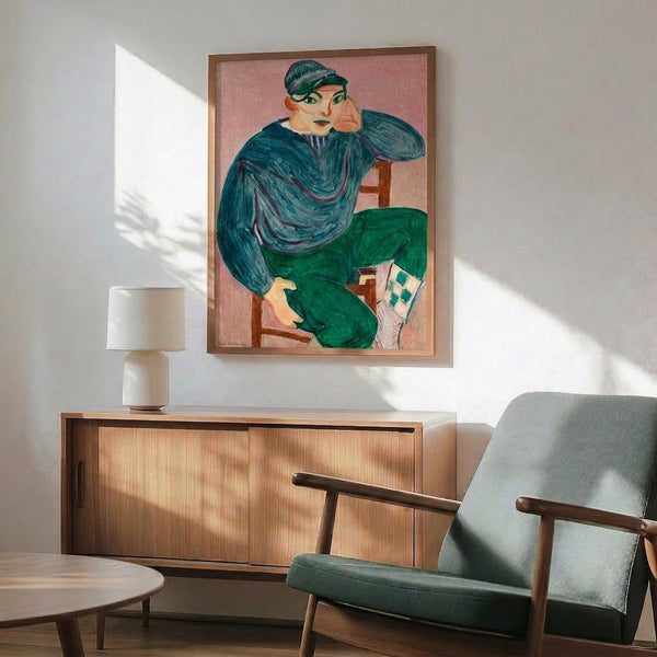 May include: Matisse portrait print in wooden frame hanging above mid-century modern sideboard with lamp, showing figure in blue shirt and green pants sitting on chair holding paper. Room has white walls, natural sunlight, teal upholstered armchair, and round coffee table creating contemporary living space mockup.