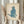 May include: Person in cream ruffled sleeves holding framed artwork and dried pampas grass against white curtained window. The vintage-style poster features a blue watercolor cat sitting upright with pink eyes on aged beige paper, displayed in light wood frame. Soft natural lighting creates warm, aesthetic home decor styling.