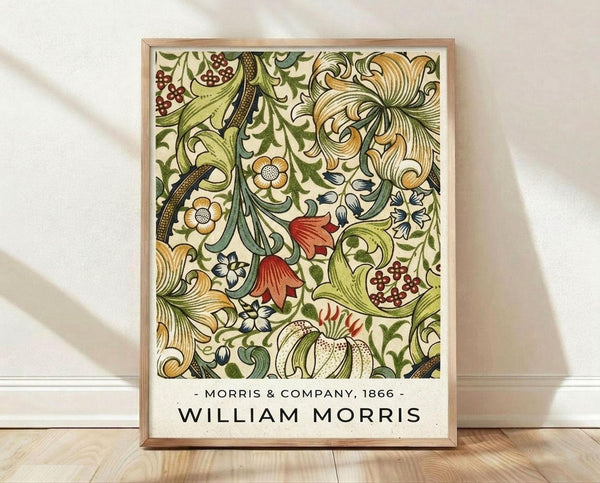 May include: Framed botanical poster with intricate Victorian-style floral pattern featuring green leaves, golden flowers, red blooms, and decorative scrollwork on cream background. Light wood frame sits on wooden floor against white wall with soft natural lighting creating gentle shadows.