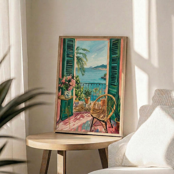 May include: Framed artwork displaying a Mediterranean balcony scene with turquoise shutters, wicker chair, potted flowers, and ocean view, positioned on a round wooden side table next to a beige upholstered chair in a sunlit room with white walls and plant shadows