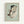 May include: Framed reproduction of an early 20th century expressionist drawing showing a crouching nude figure with dark hair against a pale green background. The artwork features loose, gestural lines in watercolor and pencil with muted earth tones. Displayed in a light wood frame on a white wall.
