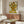 May include: Van Gogh's famous sunflowers painting displayed above a mid-century modern walnut credenza in a bright living room. The artwork shows yellow sunflowers in a vase against a cream background with yellow table surface. White upholstered chair and glass coffee table complete the stylish interior setting with natural sunlight streaming across wooden floors.