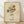 May include: Framed art print featuring a line drawing of hands holding a bouquet of stylized flowers in earth tones - yellow, orange, rust, and teal blooms with green stems. The minimalist artwork has a cream textured background, thin wooden frame, and signature marking. Displayed against white fabric backdrop on light wooden floor with natural shadows.