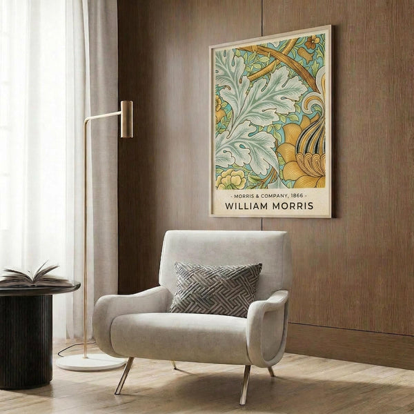 May include: Framed botanical art print with ornate green and gold foliage design hanging on wood-paneled wall above beige upholstered armchair with geometric throw pillow. Modern brass floor lamp and round black side table with open book complete the elegant reading nook scene with neutral curtains and warm lighting.