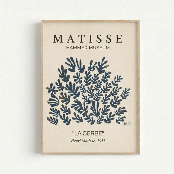 May include: Framed art print with cream background displaying abstract blue botanical cutout shapes in Henri Matisse's signature style, featuring text "MATISSE HAMMER MUSEUM" at top and "LA GERBE" with "Henri Matisse, 1953" at bottom, mounted in light wood frame against white wall
