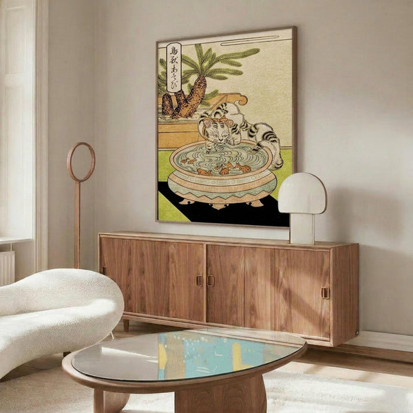 May include: Japanese woodblock print artwork featuring a striped cat drinking from a decorative ceramic bowl, with potted plants in background and Japanese text, displayed in thin frame above wooden sideboard in modern living room with white curved chair, floor lamp, and glass coffee table
