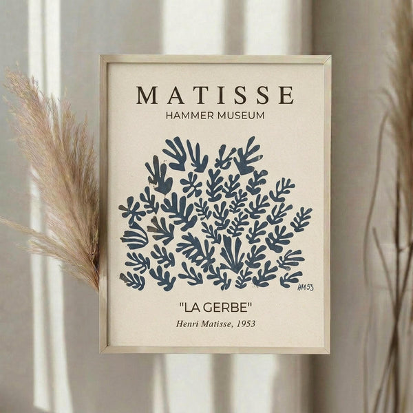May include: Framed art print displayed on neutral wall featuring Henri Matisse's blue cutout design of abstract coral-like forms on cream background. Light wood frame, museum-style text layout with title and date. Dried pampas grass visible beside frame, soft natural lighting creates gentle shadows.