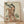 May include: Framed Japanese woodblock print artwork displayed on light wooden floor against white wall with natural lighting. Shows elegant woman in flowing orange and cream kimono with floral patterns holding decorative fan, surrounded by pine trees and foliage in traditional ukiyo-e style. Light wood frame complements the warm earth tones and delicate artistic details of the vintage-inspired reproduction print.