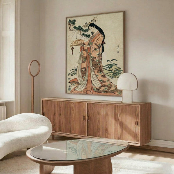 May include: Japanese woodblock print artwork showing a woman in ornate orange and cream kimono holding a decorative fan, displayed in thin wooden frame above mid-century walnut credenza with brass hardware. Modern white curved chair and glass-top oval coffee table visible in bright minimalist room with cream walls and natural lighting.