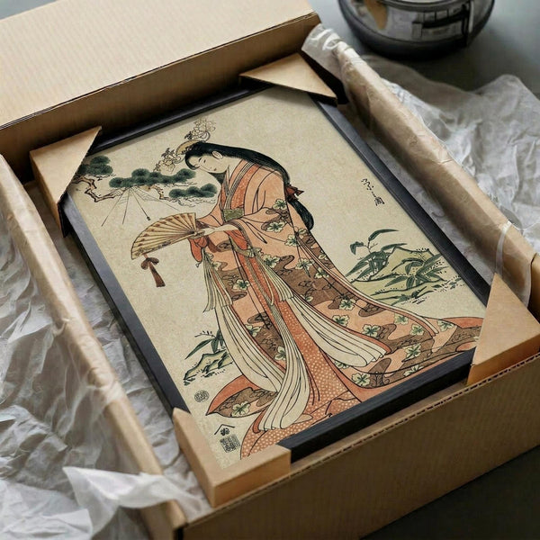 May include: Japanese woodblock print artwork displayed in black frame inside cardboard shipping box with protective wrapping. Features elegant woman in flowing orange and coral kimono with floral patterns, holding decorative fan, surrounded by green foliage. Traditional ukiyo-e art style with muted beige background and delicate linework, carefully packaged with wooden dowels for safe shipping.
