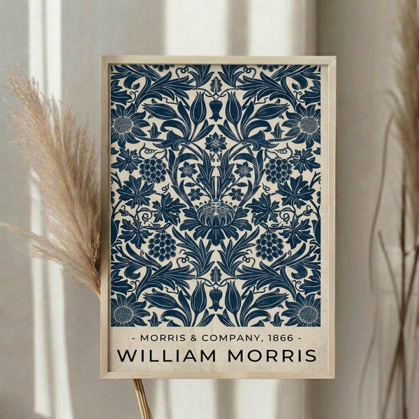 May include: Framed poster print featuring intricate blue floral damask pattern on cream background, displayed in light wood frame on neutral wall beside dried pampas grass stems. Victorian-style botanical design shows symmetrical arrangement of large blooms, grape clusters, sunflowers and ornate leaves creating decorative wallpaper motif.