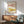May include: Framed marine illustration print featuring two lobsters with polka dot patterns - pink spotted lobster on top and yellow spotted lobster below - displayed on white wall above wooden sideboard with white ceramic lamp, next to mint green upholstered armchair with wooden frame in sunlit modern interior