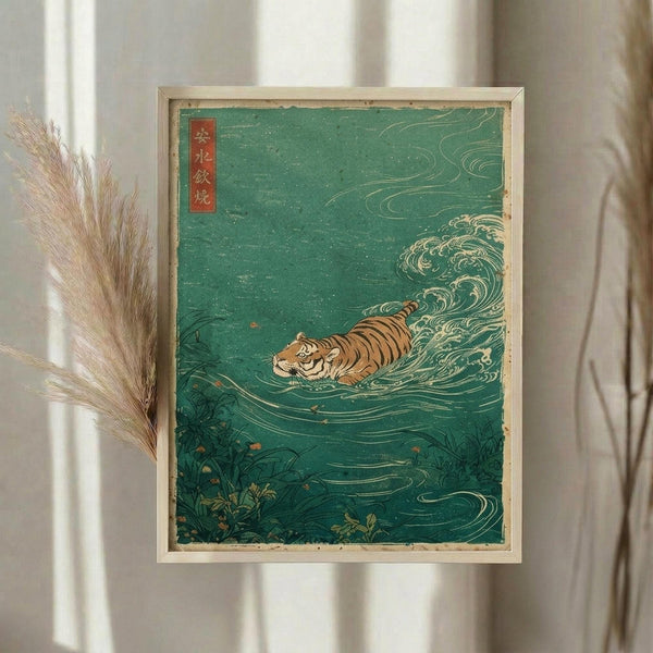 May include: Framed Japanese-style woodblock print featuring an orange and black striped tiger swimming through turquoise-green waves with white foam details, displayed on a light-colored wall next to dried pampas grass stems. The artwork shows traditional ukiyo-e styling with flowing water patterns and includes red text characters in the upper left corner within a natural wood frame.