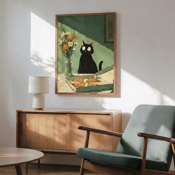 May include: Framed poster displaying a black cat with glowing yellow eyes sitting beside a vase of orange and white flowers, with pizza slices in a box on a table. The artwork features green and cream tones in a vintage illustration style. Shown hanging above a mid-century modern wooden credenza with a white ceramic lamp, next to a teal upholstered armchair with wooden frame. Sunlight streams across white walls creating geometric shadows.